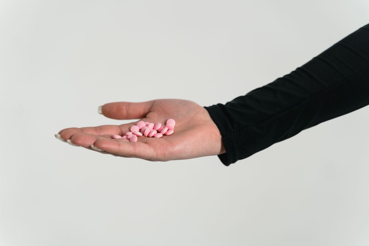 Pink contraceptive pills resting in an open hand