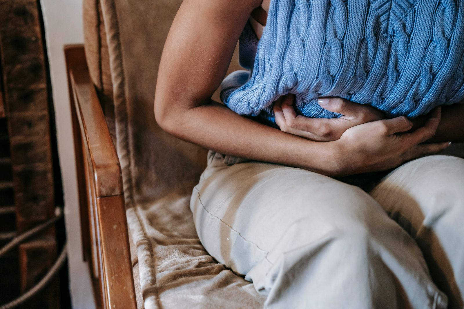 Woman holding a cushion against her abdomen while experiencing pelvic pain